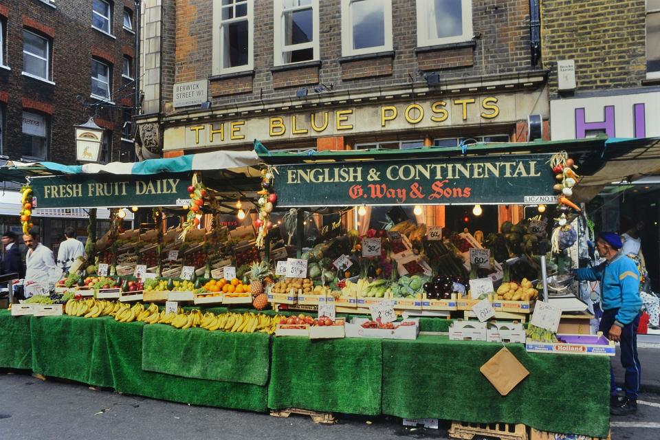 a fruit stand in front of the blue posts