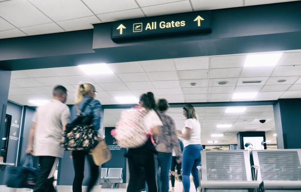 a group of people standing under a sign that says all gates