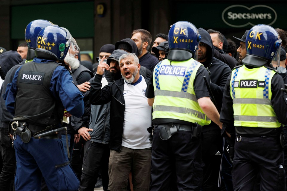 Police officers stand guard as counter-protesters push against the police cordon in Bolton