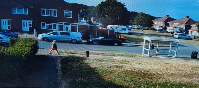 a woman is walking down a sidewalk in front of a bus stop .