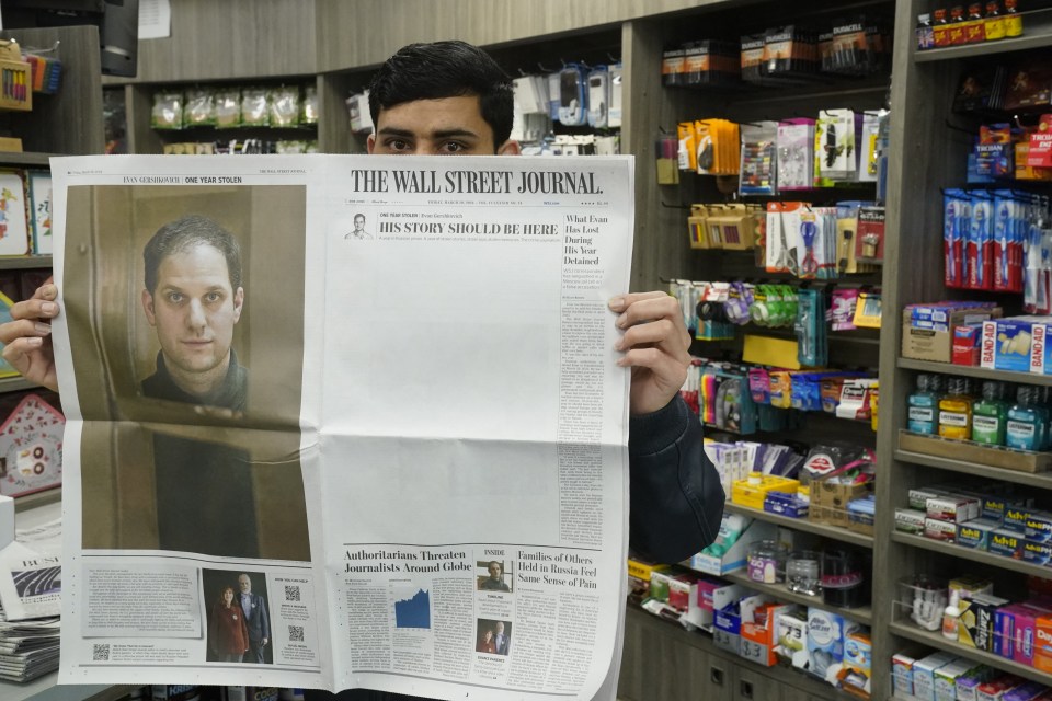 A New York City vendor poses with a March 29, 2024, copy of The Wall Street Journal showing a mostly blank front page for Evan