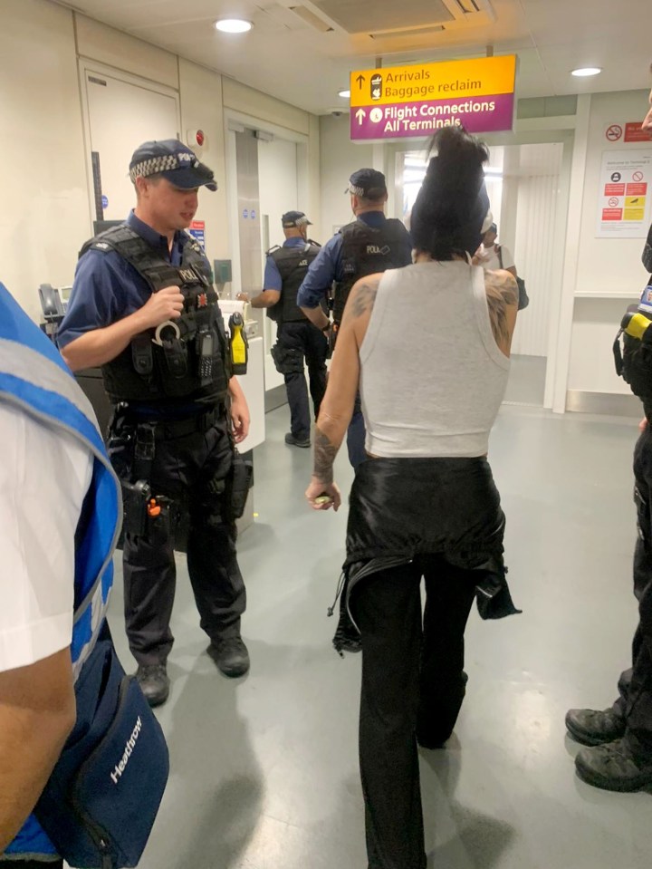 a group of police officers standing in front of a sign that says arrivals baggage restrictions and restrictions all terminals