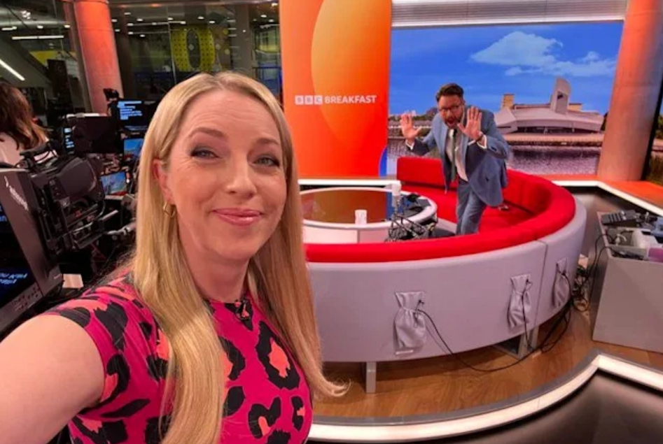 a woman taking a selfie in front of a sign that says bbc breakfast