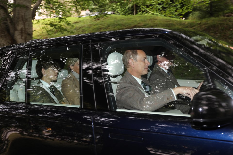 a man in a suit is driving a blue car