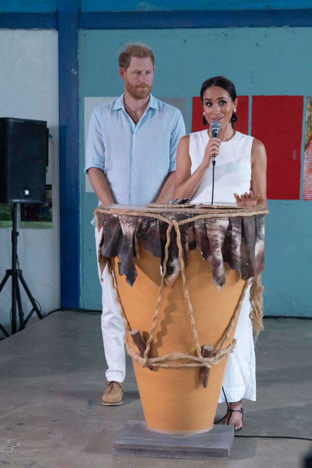 prince harry and meghan markle stand behind a large drum