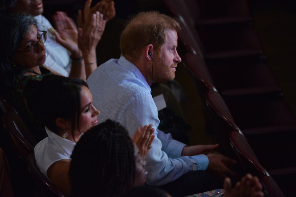 a man wearing ear buds sits in a dark auditorium