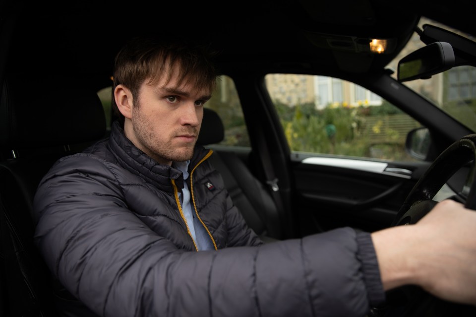 a man in a grey jacket is driving a car