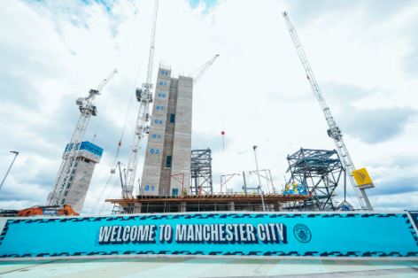 a large construction site with cranes and a sign that says welcome to manchester city .