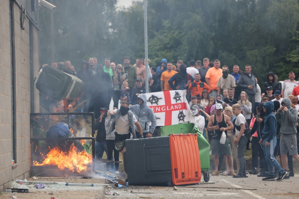 Far right thugs on the rampage hurl bins as a fire burns outside a hotel in Rotherham