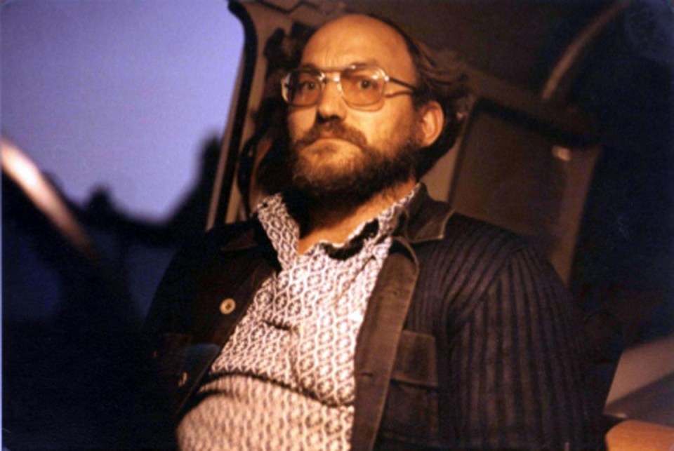 a man with glasses and a beard is sitting in a car