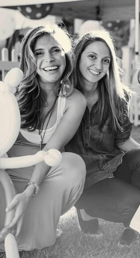 two women are sitting next to each other and smiling in a black and white photo .