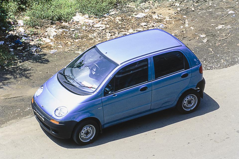 a small blue car is parked on the side of the road