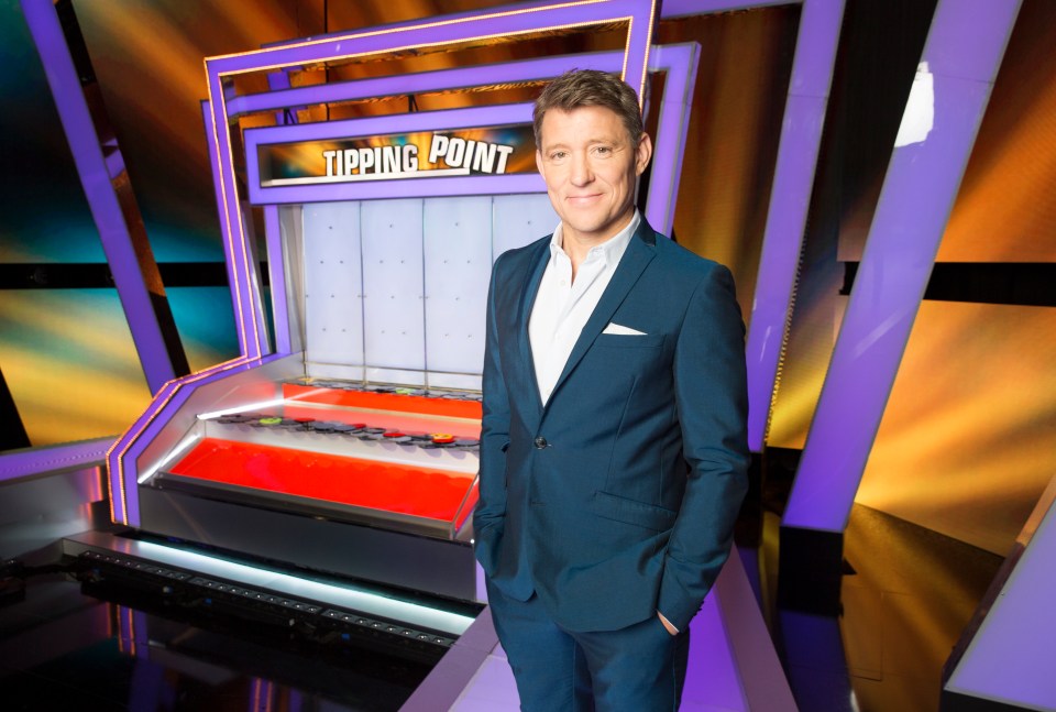 a man in a suit stands in front of a sign that says tipping point