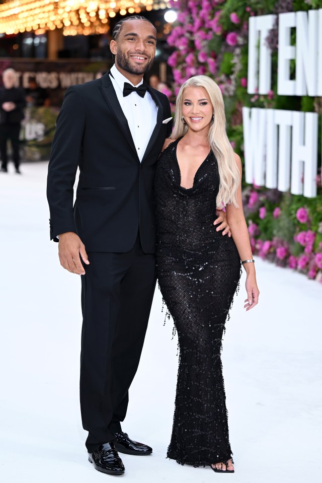 a man in a tuxedo and a woman in a black dress pose for a photo