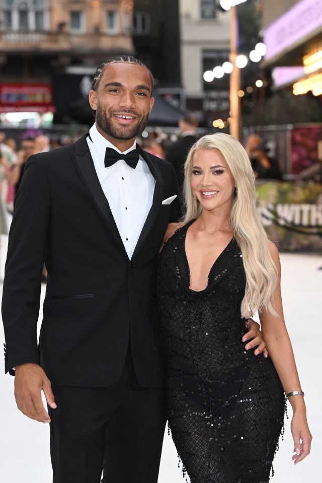 a man in a tuxedo and a woman in a black dress pose for a photo