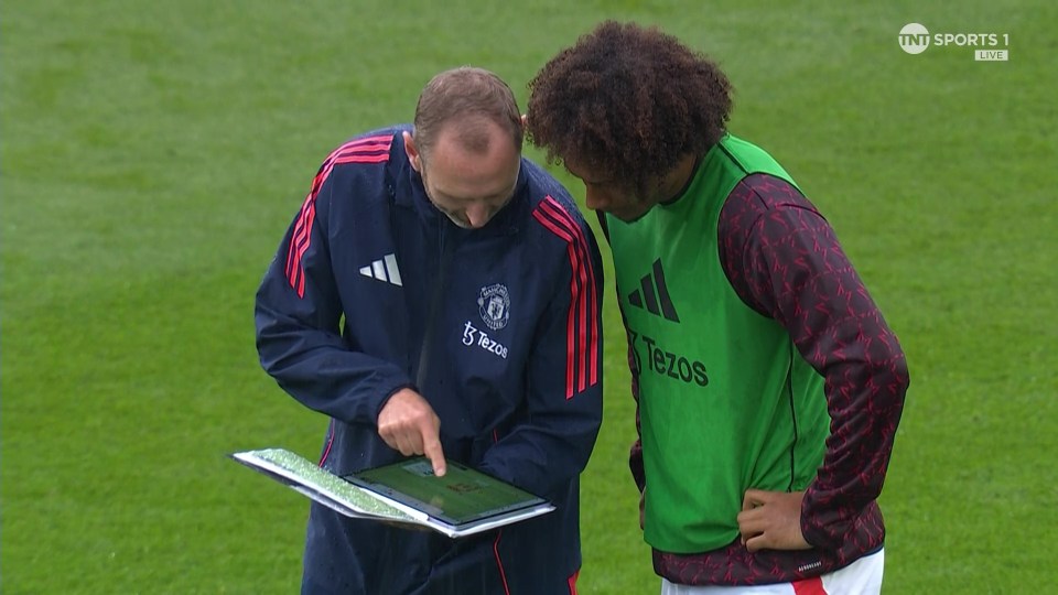 two soccer players are looking at a clipboard on a field sponsored by tnt sports 1