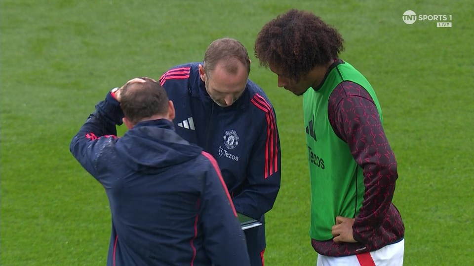 a man in a manchester united jacket talks to another man