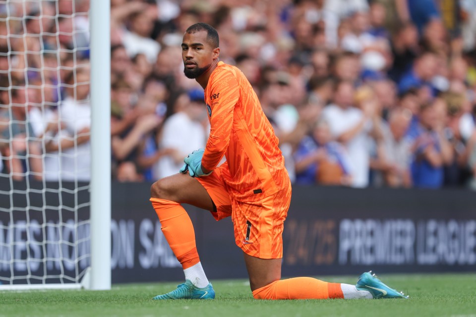 a soccer player kneeling in front of a premier league banner