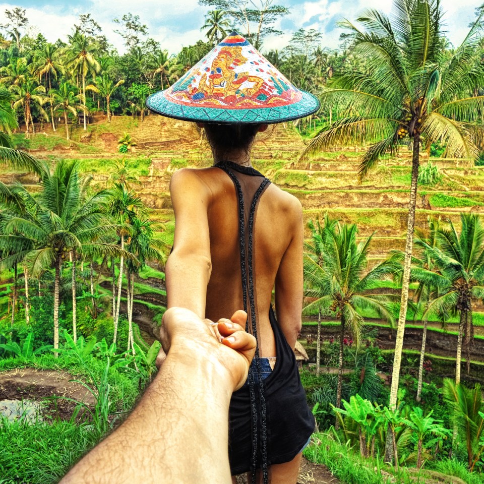 a woman wearing a colorful hat is holding a man 's hand