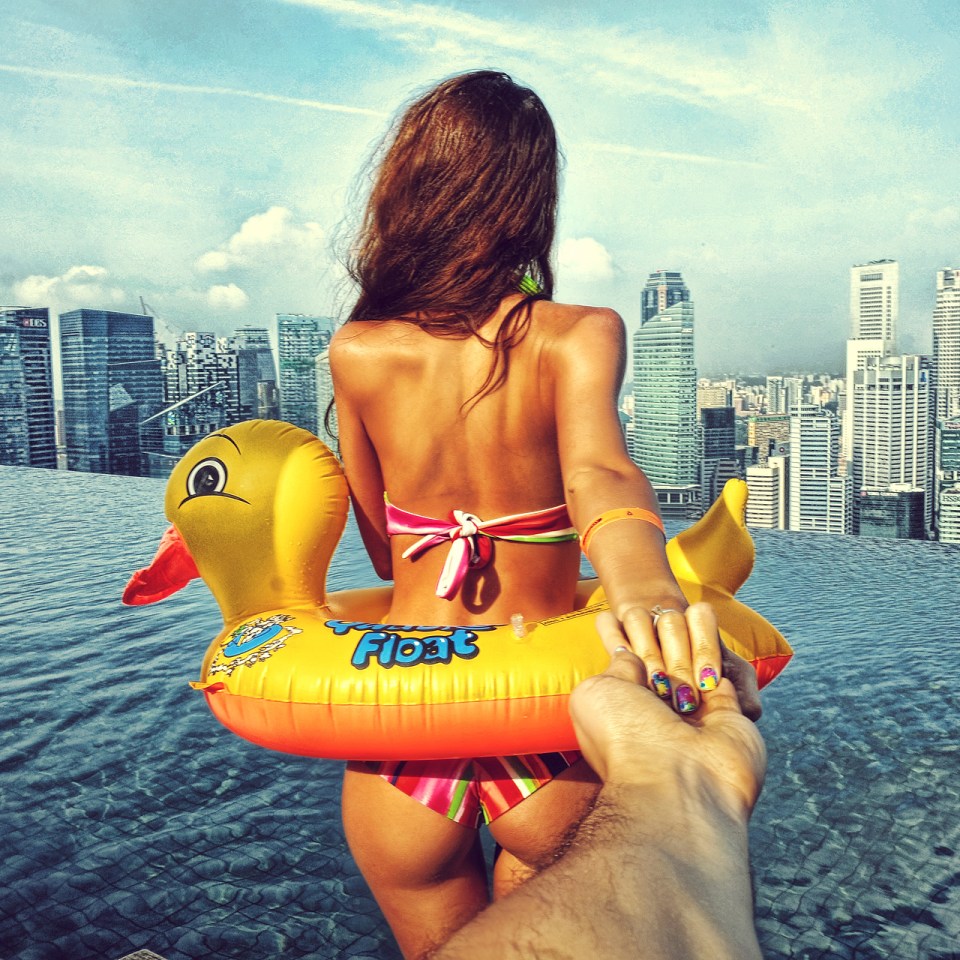 a woman in a bikini is holding a man 's hand while floating on an inflatable duck