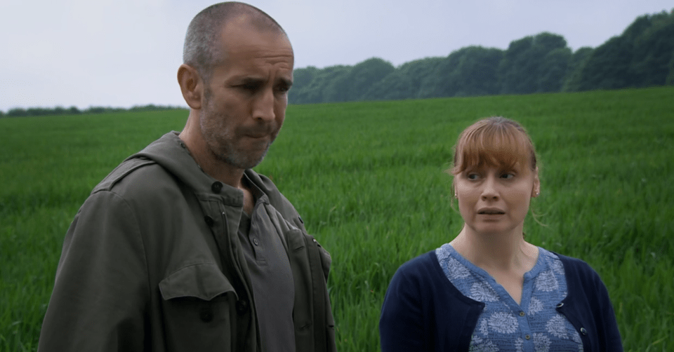 a man and a woman are standing in a grassy field