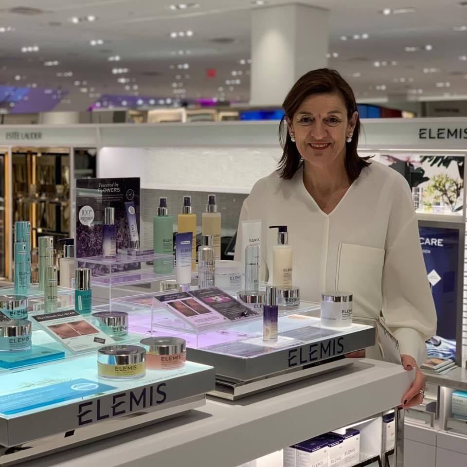 a woman stands in front of a display of elemis products