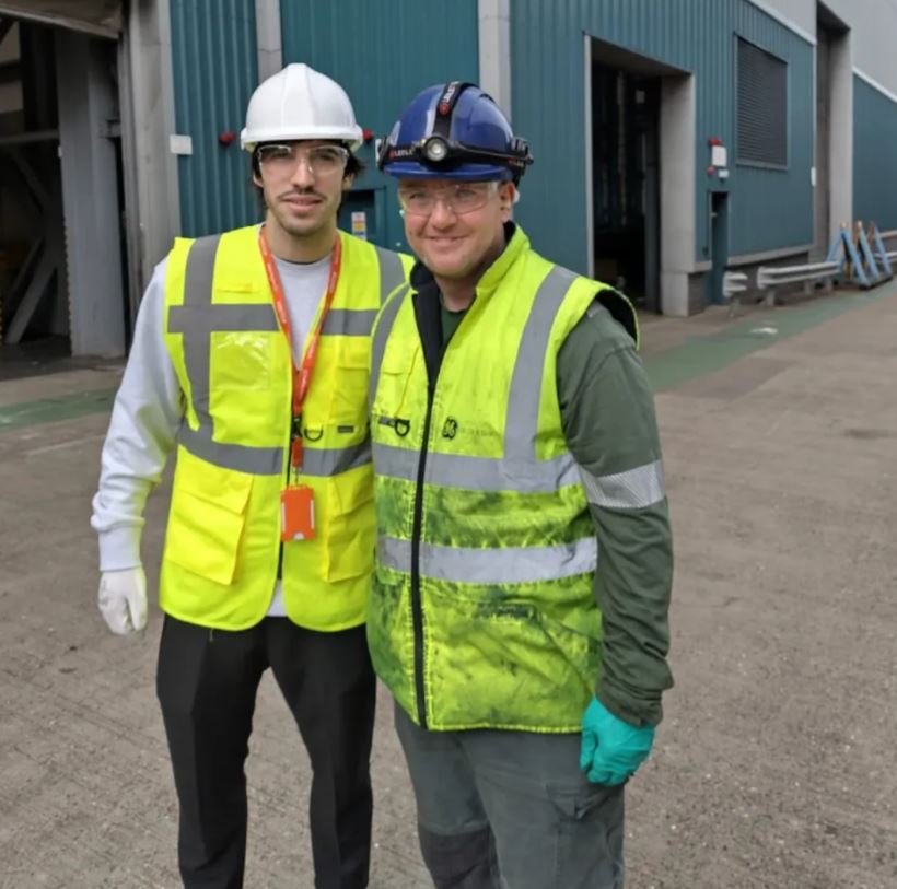 two men wearing hard hats and safety vests stand next to each other