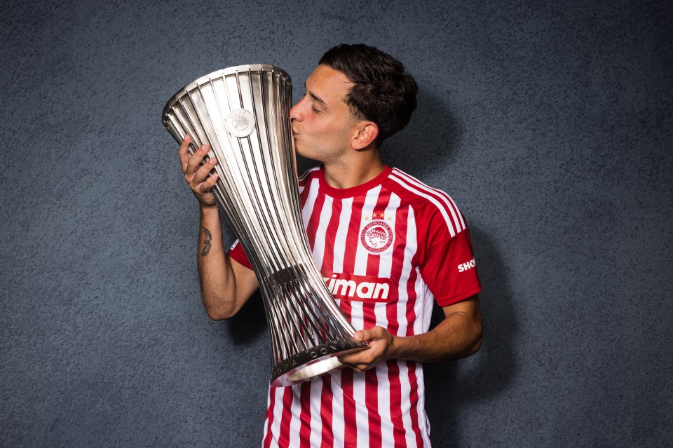 a man in a red and white striped shirt kisses a trophy