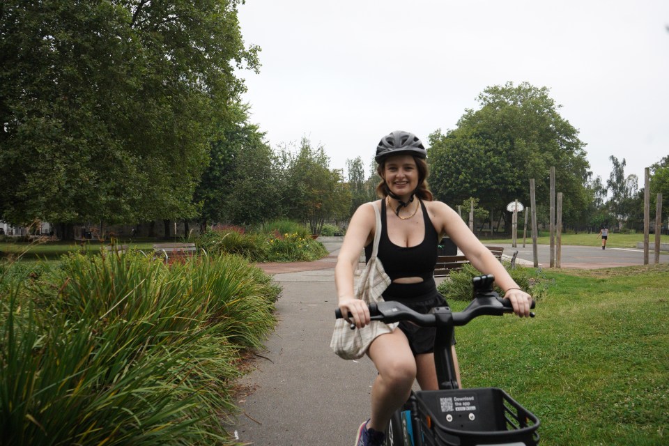 a woman wearing a helmet is riding a bike in a park