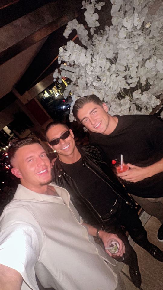 three men are posing for a picture in front of a tree with white flowers