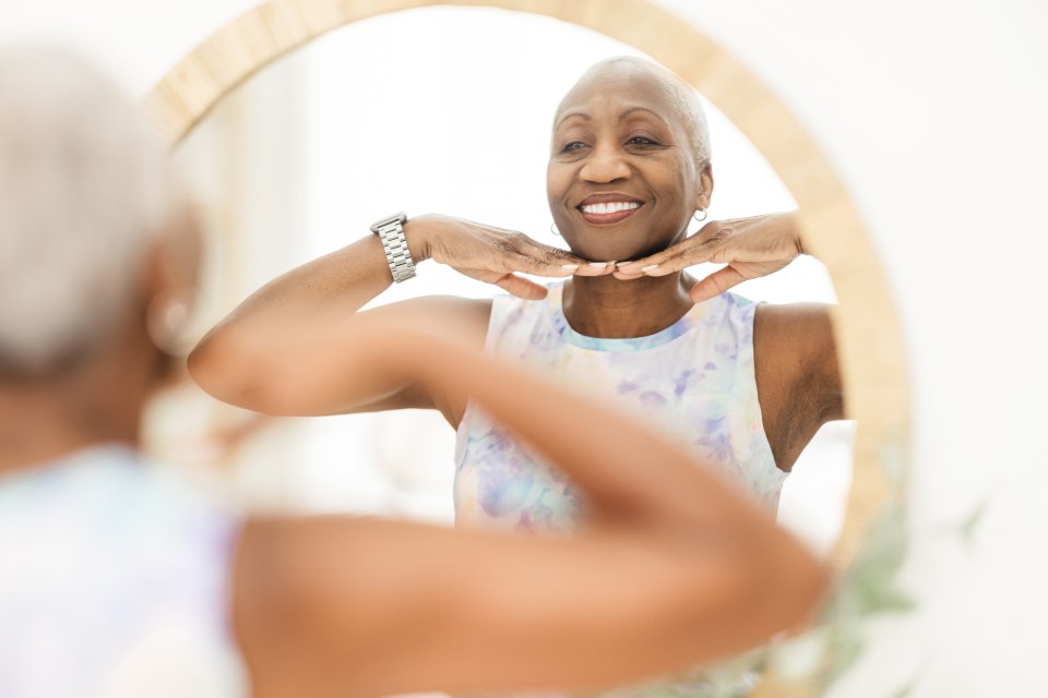 a woman smiles while looking at herself in a mirror