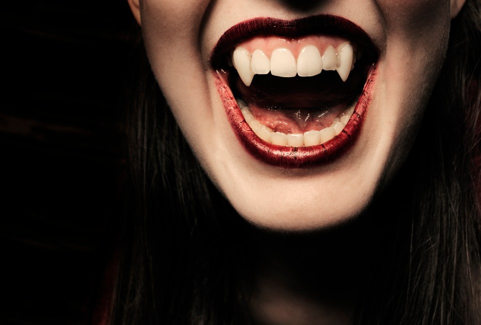 a close up of a woman 's mouth with vampire teeth