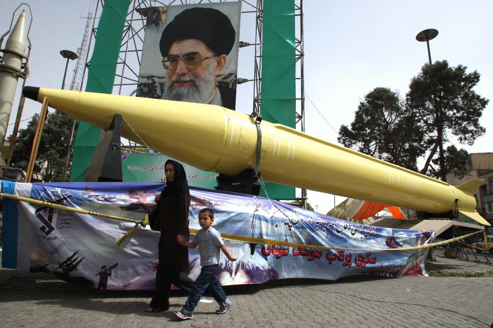 An Iranian woman and her son walk past a Shahab-3 missile