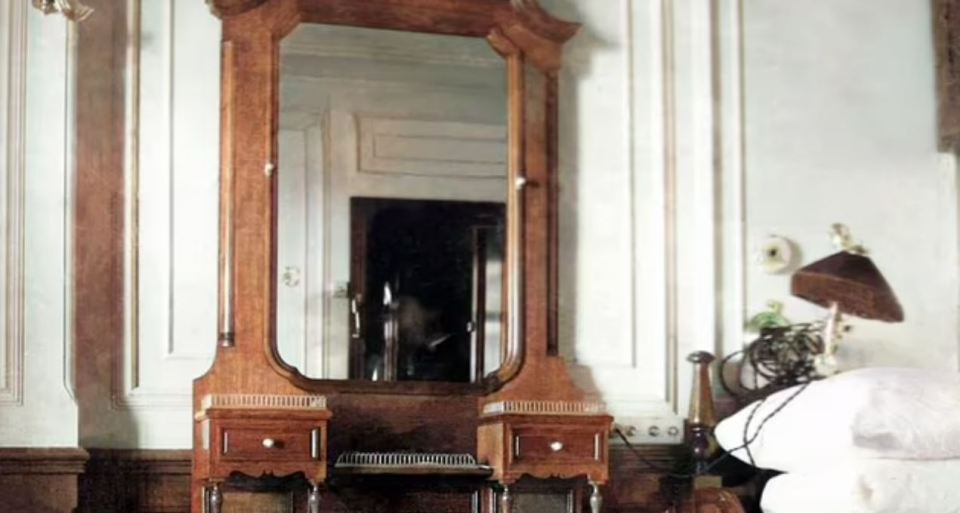 a wooden vanity with a mirror and two nightstands in a bedroom .