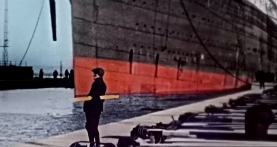 a man is standing in front of a large ship in the water .