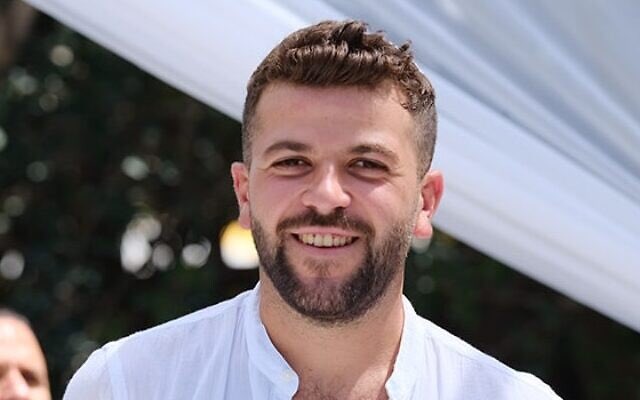 a man with a beard is wearing a white shirt and smiling .