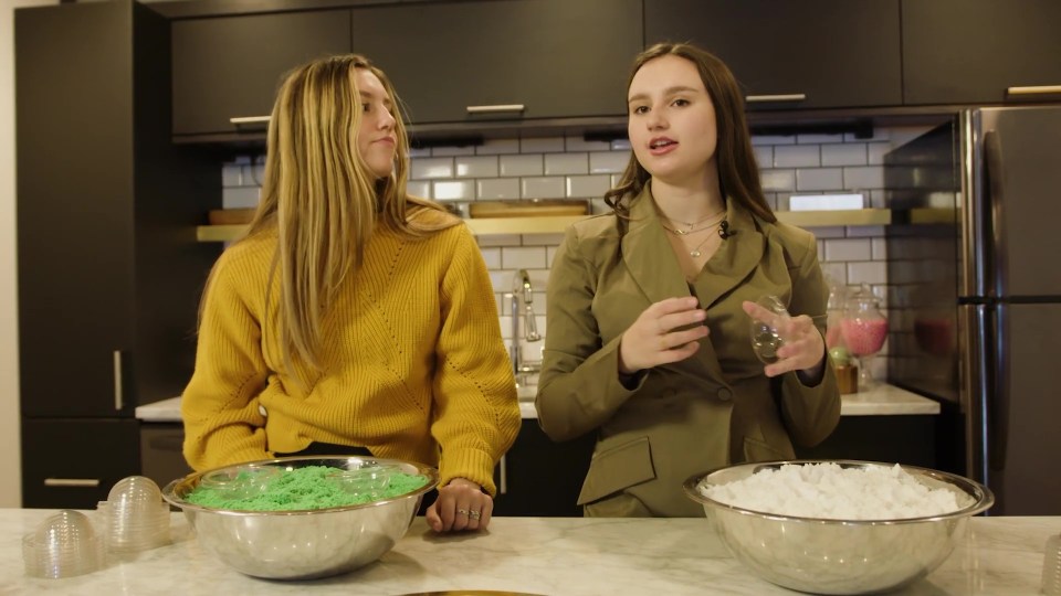 a woman in a yellow sweater stands next to a woman in a green jacket