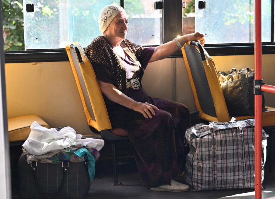 An elderly woman on a bus with her little belongings