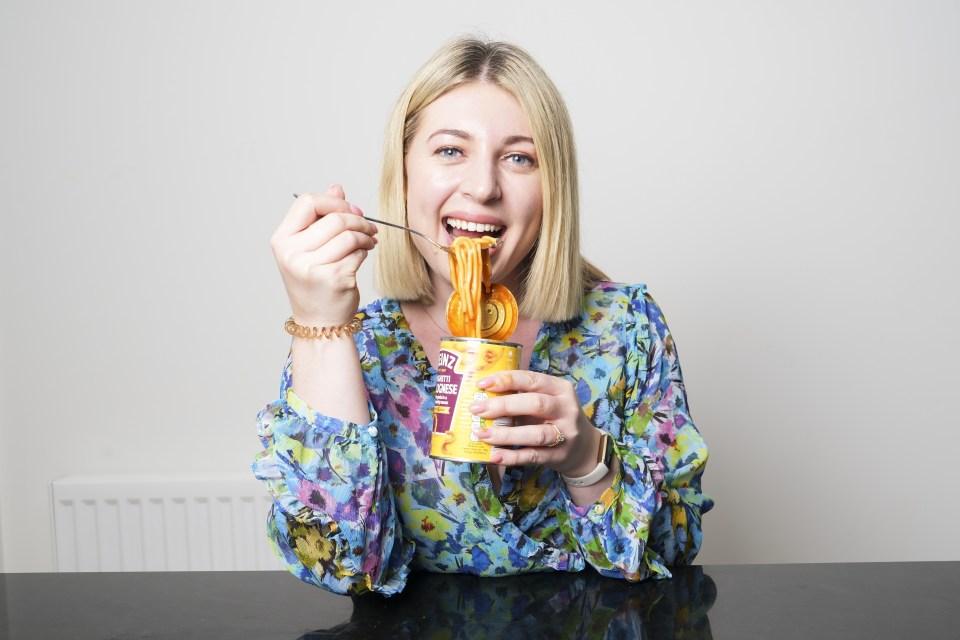 a woman is eating noodles from a can with a spoon