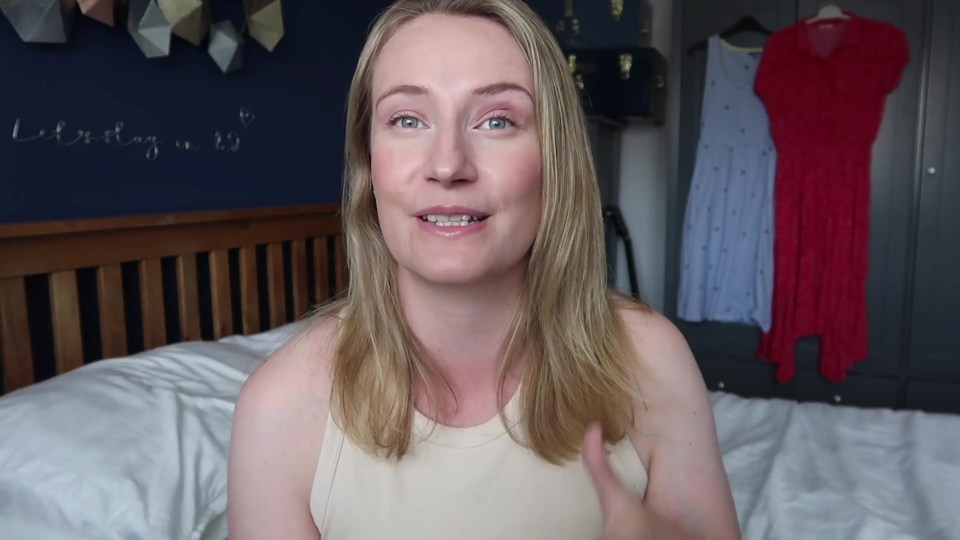 a woman sitting on a bed in front of a wall that says " let 's stay in it "