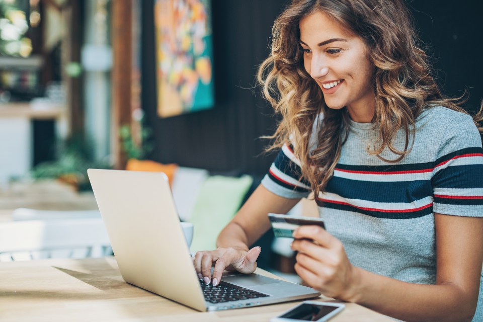 a woman is using a laptop and holding a credit card