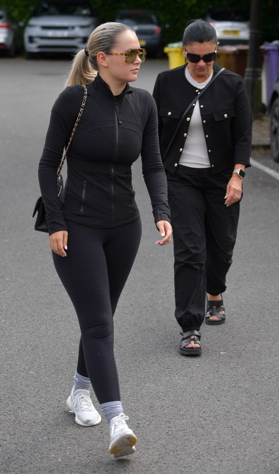 two women walking down a street with one wearing sunglasses