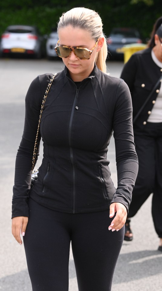 a woman wearing sunglasses and a black jacket is walking down the street