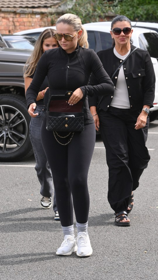 a woman wearing sunglasses and a black purse walks down the street