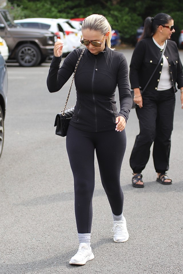 a woman in a black jacket and leggings is walking down the street