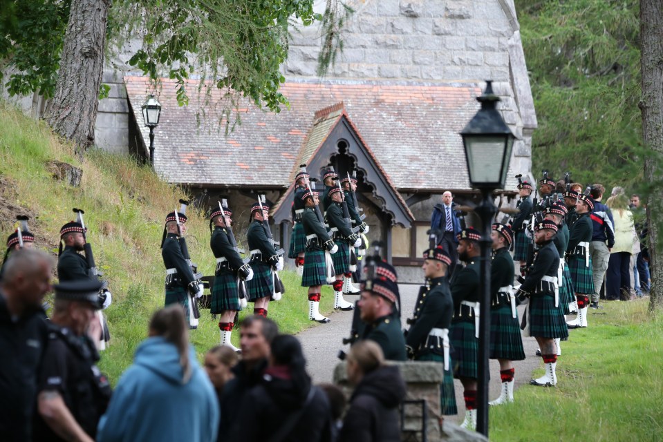 a group of men in kilts marching in front of a church