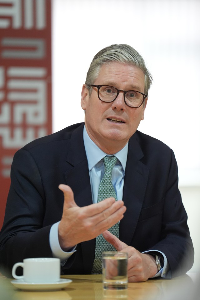 a man in a suit and tie is sitting at a table with his hands outstretched