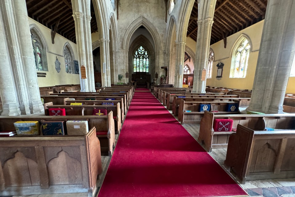 the inside of a church with rows of wooden benches and a red carpet