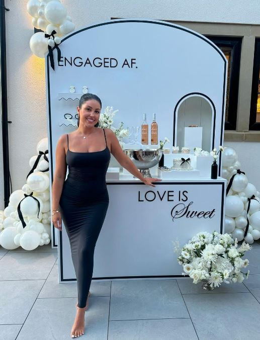 a woman in a black dress is standing in front of a sign that says love is sweet