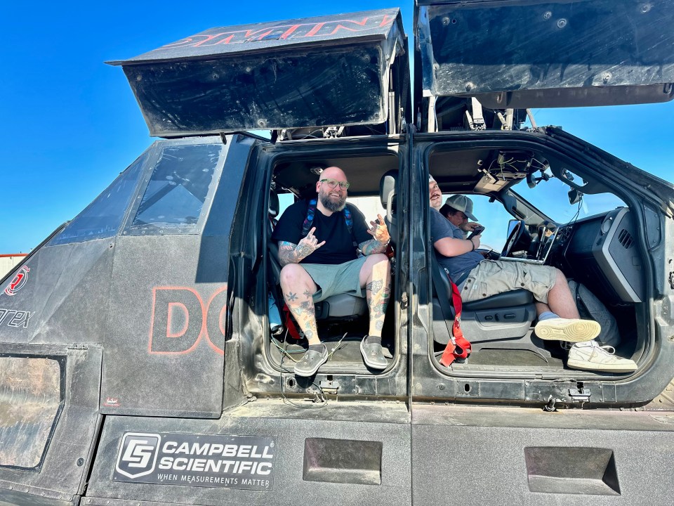 two men are sitting in a vehicle that says campbell scientific